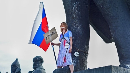 В Новосибирске студентка в ночнушке и с российским флагом приковала себя цепями к памятнику Ленина