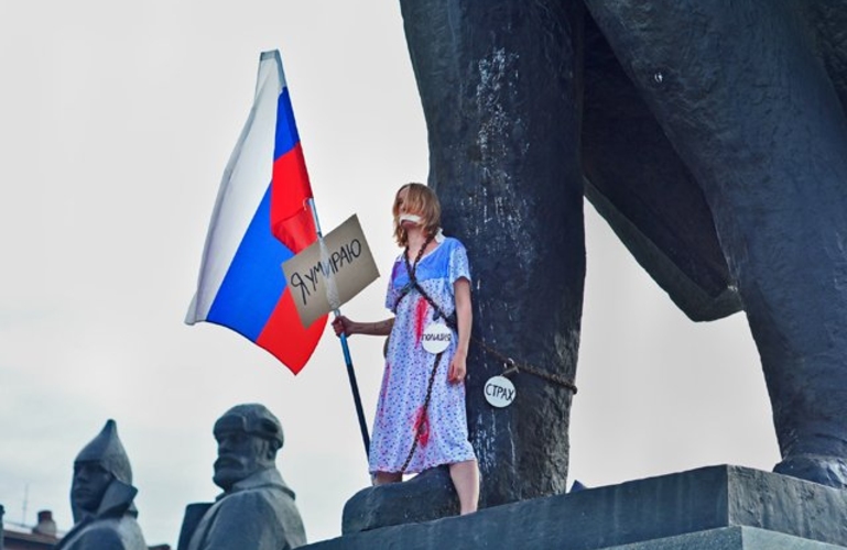 В Новосибирске студентка в ночнушке и с российским флагом приковала себя цепями к памятнику Ленина